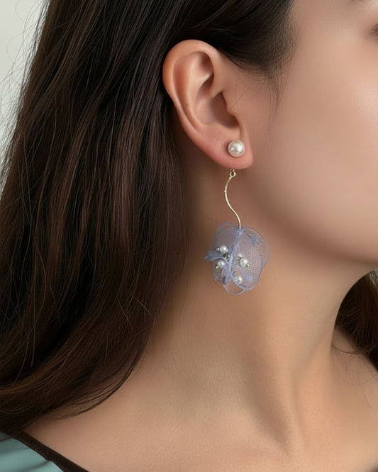 Close-up of an earring with a floral design worn by a person.