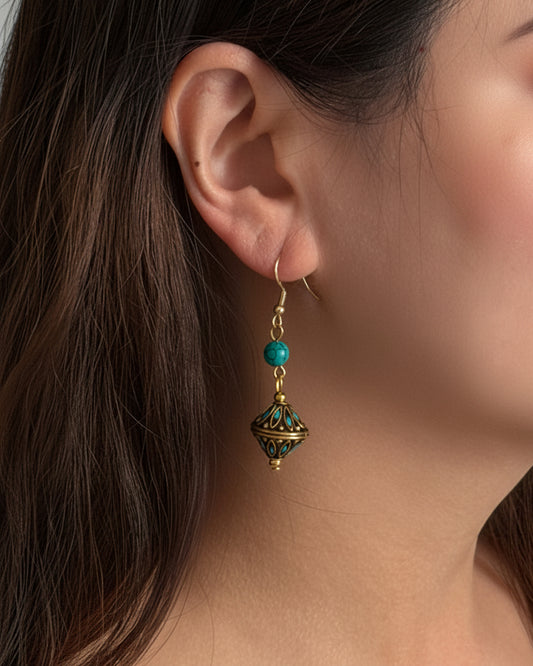 Close-up of an earring worn by a person with dark hair.