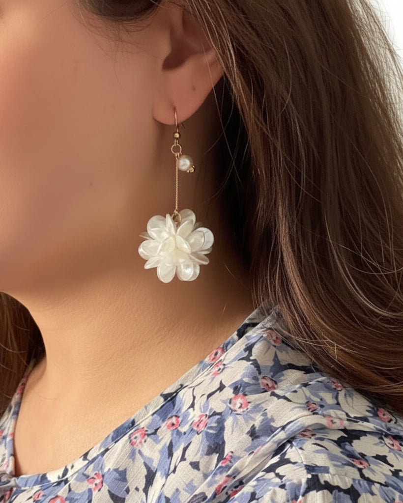 Close-up of a person wearing a floral earring with a white flower design.
