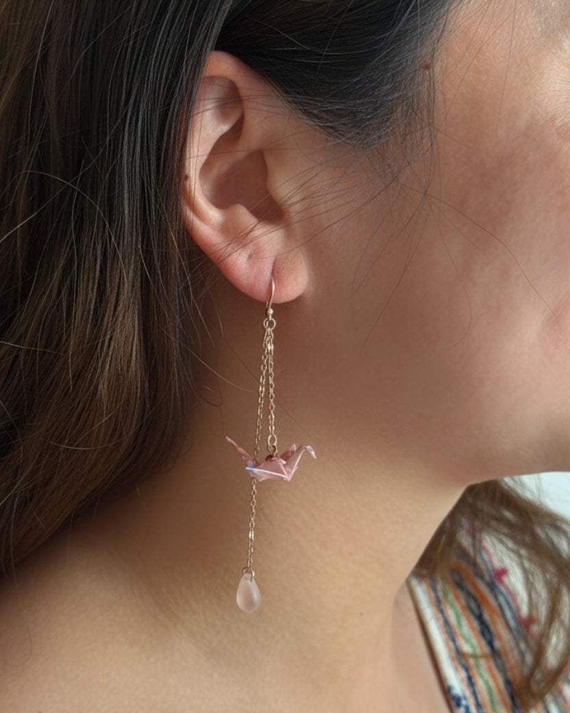 Model wearing blush pink origami crane earrings with long drop chains
