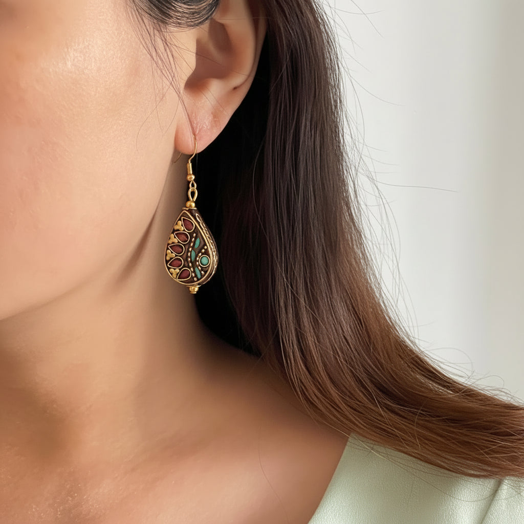 Close-up of a woman wearing a nepal artisan earring on a plain background