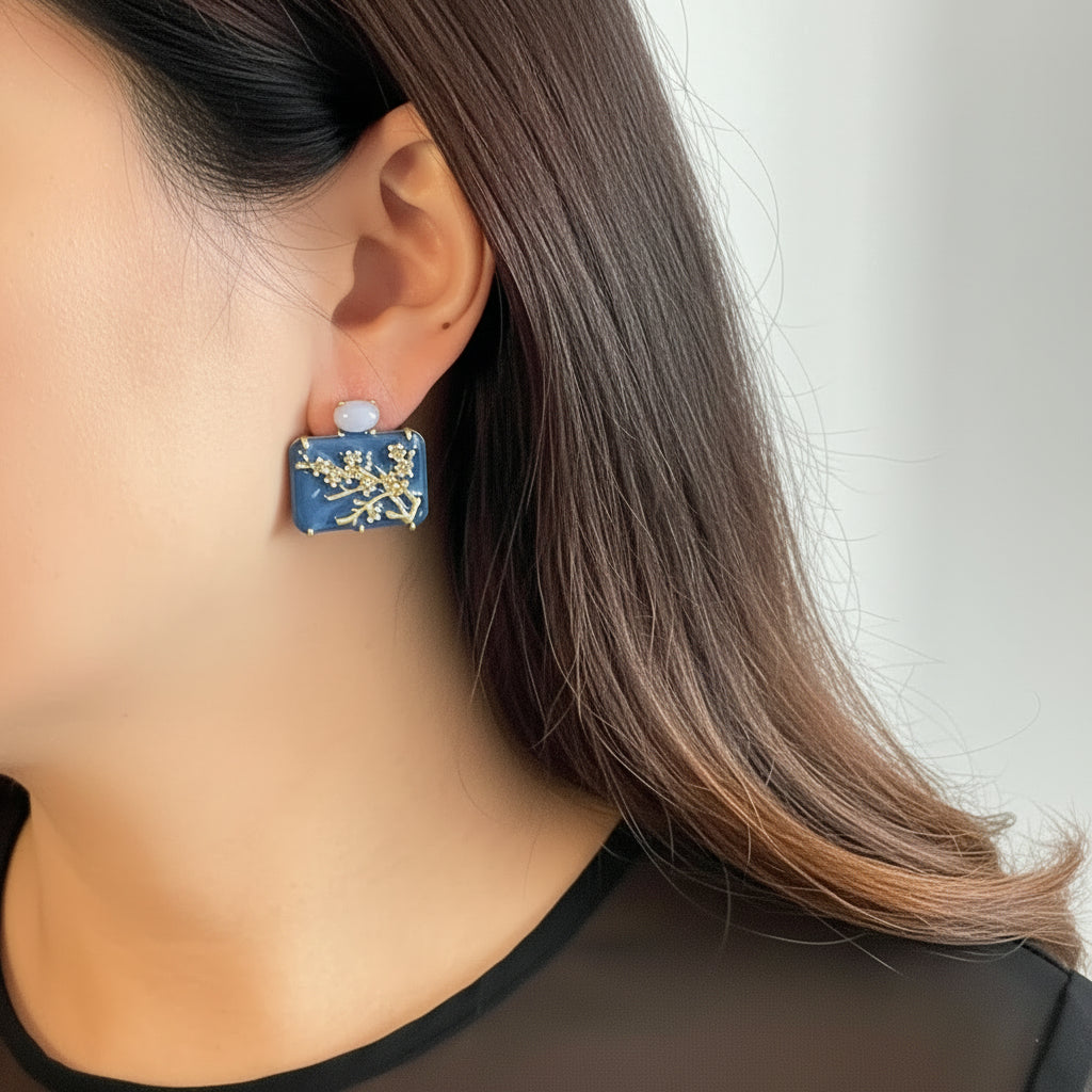 Close-up of a person wearing a blue floral earring with a plain background