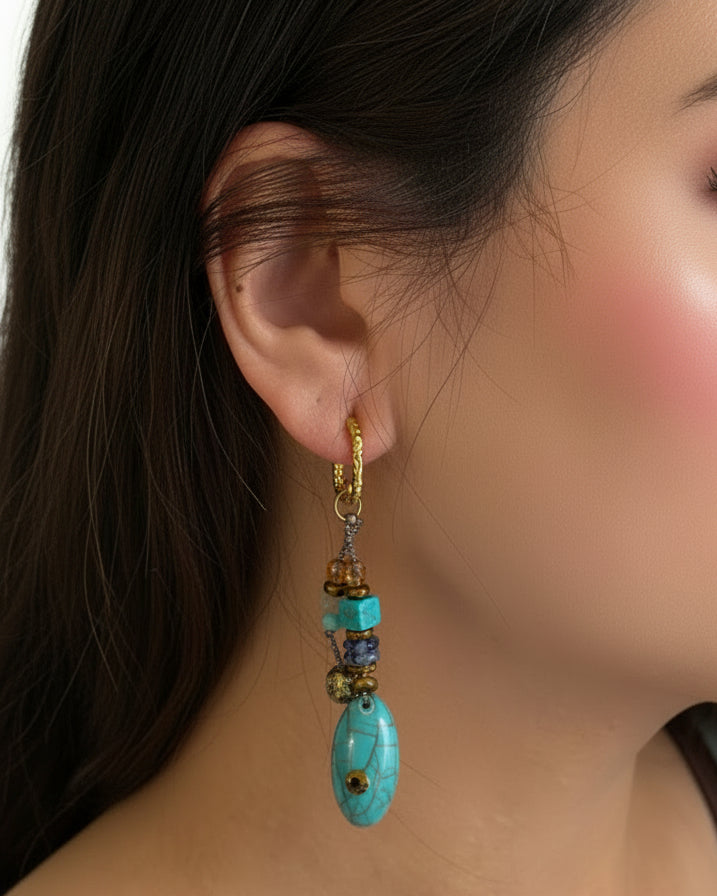Close-up of an ear with a decorative earring featuring blue and gold elements.