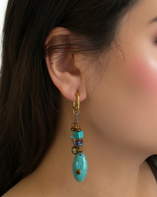 Close-up of an ear with a decorative earring featuring blue and gold elements.
